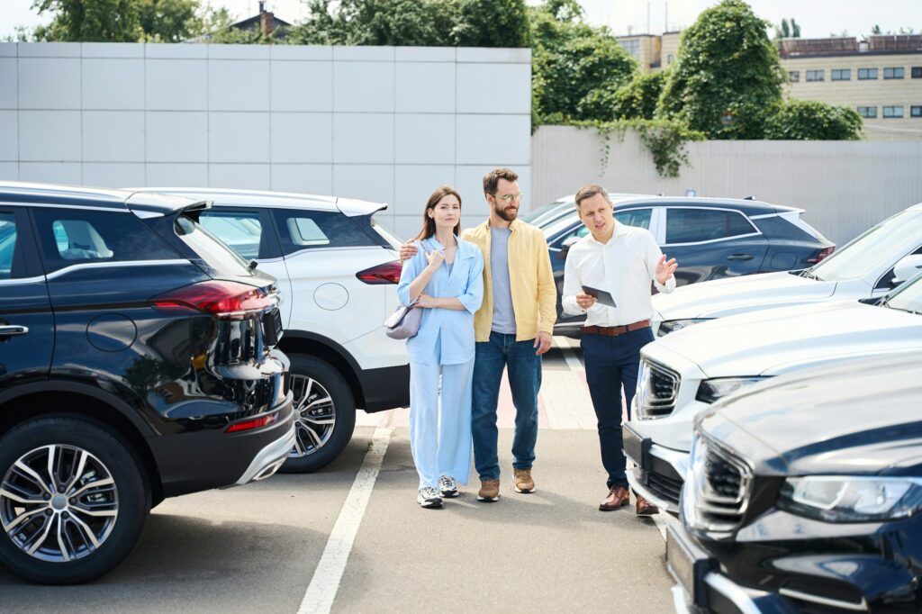 Wife and husband choose car in yard of car dealership